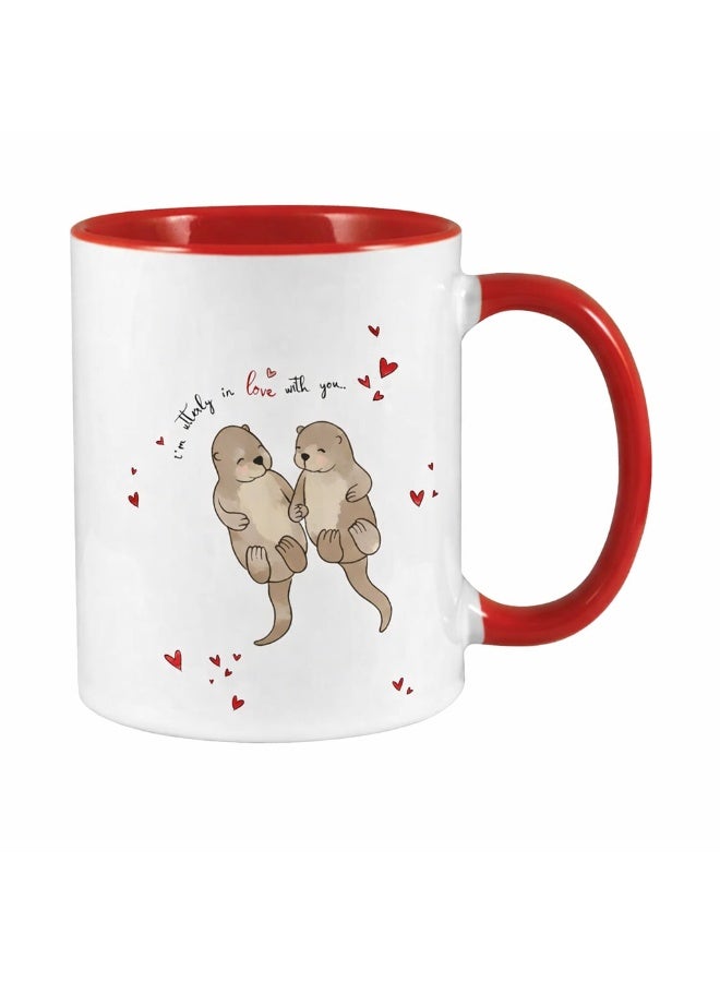 ميلز كوب سيراميك أحمر بلونين، عليه صورة زوجين لطيفين من ثعالب الماء يمسكان بأيدي بعضهما البعض، مكتوب عليه "مغرمان تمامًا". - Image 1